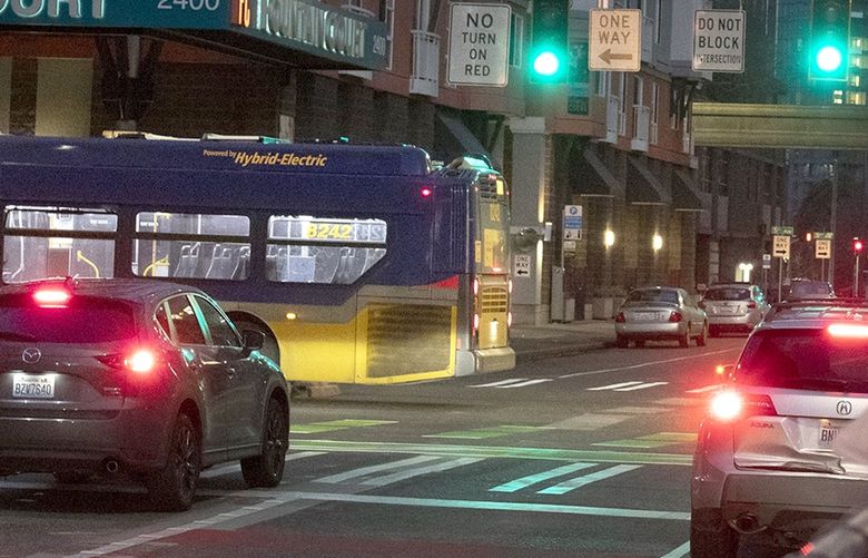 At right, a new camera sign warns drivers not to block the intersection at 4th and Battery, Monday, Nov. 29, 2021 in Seattle. At left, part of a bus sticks out into the intersection. 218878