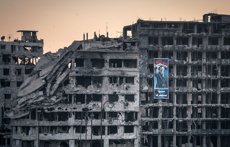 FILE -A poster of President Bashar al-Assad hangs from the ruins of a shopping mall in Homs, Syria, June 15, 2014. Powerful associates of Syria’s president are making and selling captagon, an illegal amphetamine, creating a new narcostate on the Mediterranean. (Sergey Ponomarev/The New York Times) XNYT22 XNYT22