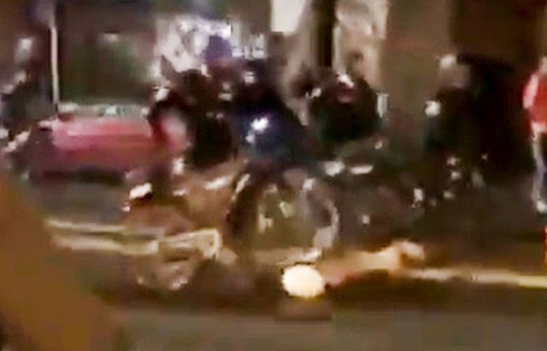 A screen grab from a video shows a Seattle Police officer roll a bike’s tires over the head of a person lying in the road early Thursday after a night of protest.