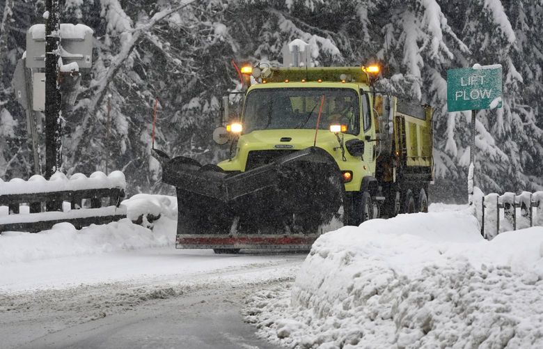 A Washington Dept. of Transportation snow plow drives near a maintenance facility near Interstate Highway 90, Thursday, Dec. 9, 2021, as snow falls near Snoqualmie Pass in Washington state. More U.S. drivers could find themselves stuck on snowy highways or have their travel delayed this winter due to a shortage of snowplow drivers as some states are having trouble finding enough people willing to take the jobs. (AP Photo/Ted S. Warren) WATW202 WATW202