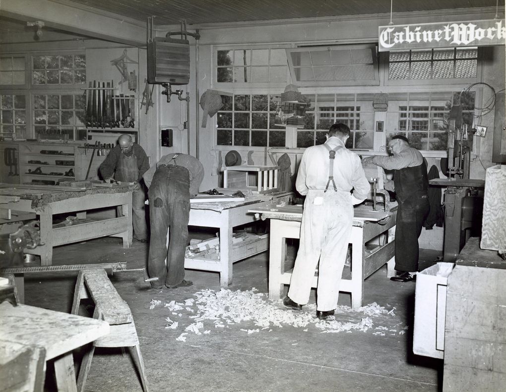 Four men in a workshop, under a sign saying, “Cabinet Work” at Northern State Hospital in 1946. (Ebbert T. Webber / Washington State Archives)