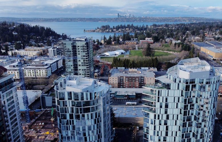 Seen from the air, Bellevue’s Soma Towers apartments loom large in the foreground, overlooking Bellevue Downtown Park at center, while downtown Seattle’s skyscrapers are seen in the distance, Sunday, Dec. 12, 2021. Jon Talton writes about how Bellevue and Seattle fortunes are intertwined — they’re complementary, but they’re also competitors, and there have been good times and bad for both. 219061