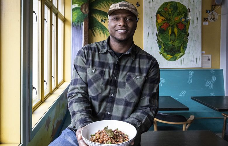 Wed. December 15, 2021.     Trey Lamont, Chef/owner of the Jerk Shack serves black-eyed peas and rice and peas, dishes that have roots in West Africa that are a symbol of a culture that survived slavery.  He’s holding a bowl of his black-eyed peas.   219090