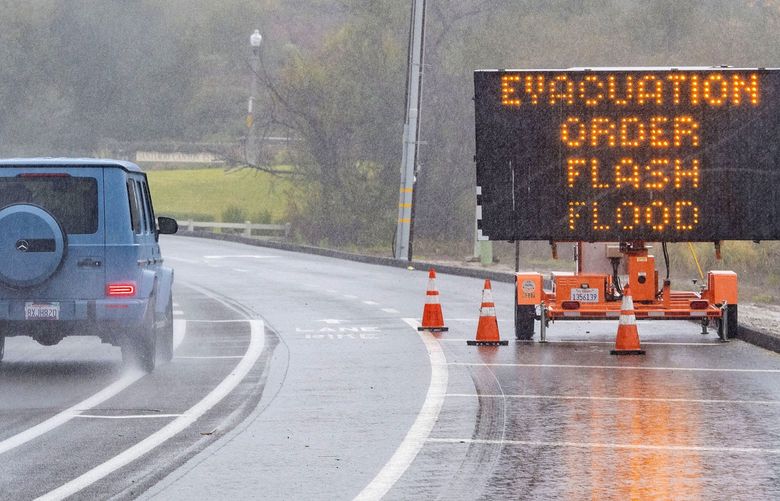 A vehicle passes by a evacuation order sign for the canyons in eastern Orange County, Calif., along E. Santiago Canyon Road in Trabuco Canyon as a winter storm brought heavy rain, high winds and flash flooding to Orange County and Southern California, Tuesday, Dec. 14, 2021. (Mark Rightmire/The Orange County Register via AP) CAANR300 CAANR300