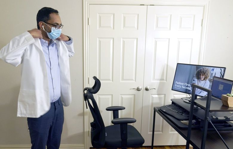 FILE – Medical director of Doctor on Demand Dr. Vibin Roy prepares to conduct an online visit with a patient from his work station at home, April 23, 2021, in Keller, Texas.  Comfort levels with remote care can vary depending on factors like age, income level or race, according to the survey from The Associated Press-NORC Center for Public Affairs Research.  (AP Photo/LM Otero, File) WX301 WX301