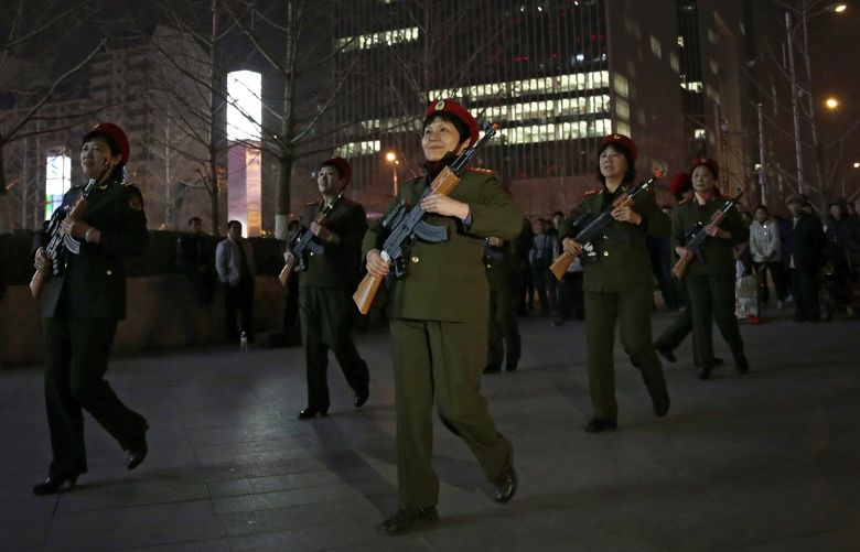 In this Tuesday, March 24, 2015 photo, Chinese women holding toy guns march to a revolutionary song during their daily exercises at a square outside a shopping mall in Beijing. The group is a part of senior health trend that has filled squares and apartment courtyards across China, winning the admiration of medical experts but upsetting neighbors over the noise level. (AP Photo/Andy Wong)