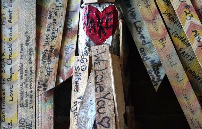 Messages on wood from friends and family hang as feathers on a sculpture by Laura Panozzo at the Play For Jake Foundation, named after Julie West’s 17-year-old son who died in 2013, of sudden cardiac arrest, Thursday, Dec. 16, 2021, in La Porte, Ind. His death, well before the pandemic, has not stopped news coverage of his collapse from being misappropriated online in a widely shared video designed to cast doubt on COVID-19 vaccination. (AP Photo/Charles Rex Arbogast) INCA104 INCA104