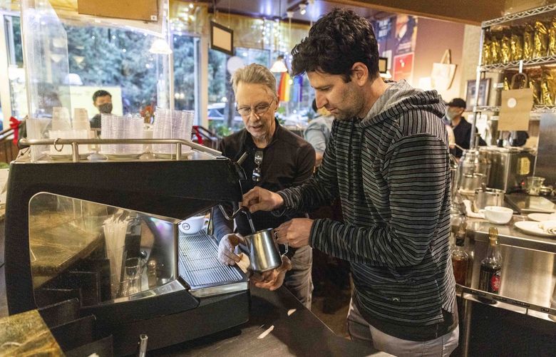 Founder David Schomer, left, shows Daniel Seddiqui how to create latte art at a coffee machine at Espresso Vivace Alley 24 in South Lake Union in Seattle on Dec. 15, 2021. 

Daniel Seddiqui, 39, a California native who now lives in Oregon, travels to the major cities in the United States to learn unique crafts meaningful to each location. For example, he learned about bikes in Portland and graffiti art in Brooklyn. He describes Seattle being the 49th city on his list of 65: for Seattle, he foraged for mushrooms and learned the basics of latte art. Seddiqui describes that he does not like the bitter taste of coffee and had his first cappuccino with Schomer.