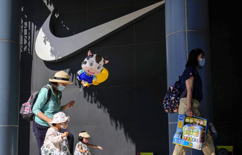 A woman and children wearing masks pass by Nike store in Beijing on Thursday, June 3, 2021. The Chinese government has accused H&M, Nike, Zara and other brands of importing unsafe or poor quality children’s clothes and other goods, adding to headaches for foreign companies after Beijing attacked them over complaints about possible forced labor in the country’s northwest. (AP Photo/Ng Han Guan) XHG115