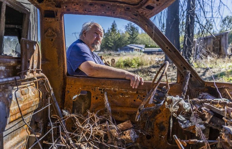 Darrell Herde, 72, leans on his car that was destroyed in the 244th Command Fire in Graham, Wash., over a year ago.