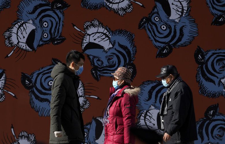 People wearing face masks to help curb the spread of the coronavirus walk by a billboard depicting a cartoon tigers, a Chinese zodiac which marks the upcoming year 2022, at a shopping mall in Beijing, Sunday, Dec. 19, 2021. The omicron variant of the coronavirus has been detected in 89 countries, and COVID-19 cases involving the variant are doubling every 1.5 to 3 days in places with community transmission and not just infections acquired abroad, the World Health Organization said on Saturday. (AP Photo/Andy Wong) XAW102 XAW102