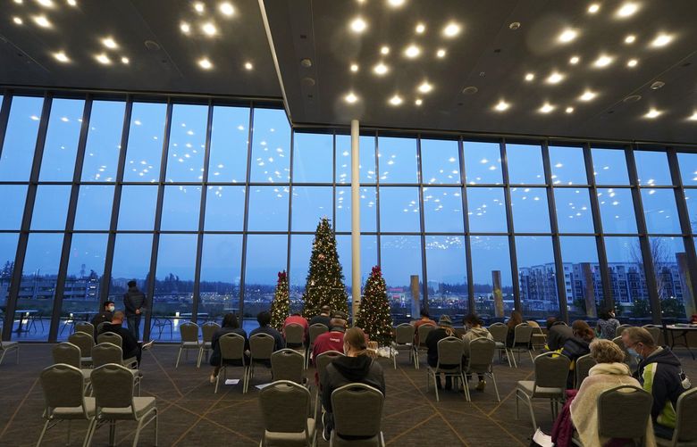 People wait in an observation area at the Federal Way Performing Arts and Events Center, Monday, Dec. 20, 2021, on the first day of a COVID-19 vaccination clinic in Federal Way, Wash., operated by King County Public Health and other partners with support from the Federal Emergency Management Agency. FEMA staff and contract workers have been traveling across the U.S. to set up temporary community vaccination centers, including mobile bus-based clinics, in efforts to increase the availability of COVID-19 vaccinations and booster shots. (AP Photo/Ted S. Warren) WATW107 WATW107