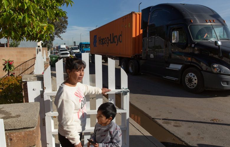 Imelda Ulloa with her grandson Anthony Maganá outside her home in the Wilmington neighborhood of Los Angeles Dec. 15, 2021. Traffic spilling over from the backlogged port has brought noise, pollution and safety hazards. (Allison Zaucha/The New York Times) XNYT14 XNYT14