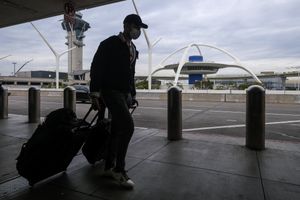 一名旅客于 12 月 22 日星期三抵达洛杉矶国际机场。 (Ringo HW Chiu / 美联社)
