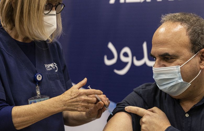 A staffer at the Sheba Medical Center receives a fourth dose of Pfizer-BioNTech COVID-19 vaccine, in Ramat Gan, Israel, Monday, Dec. 27, 2021. Israel began trials of a fourth dose of coronavirus vaccine on Monday with 150 medical personnel who received a booster dose in August in what is believed to be the first study of its kind. (AP Photo/Tsafrir Abayov) XOB103 XOB103