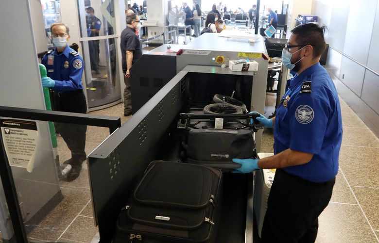 Lead Transportation Security Officer Enrique Rodriguez, right, mans an x-ray machine, Wednesday, Sept. 1, 2021 at Sea-Tac Airport. Rodriguez said he initially joined with the goal to stay a short time but he kept moving up and now has 5 years with TSA. 218087