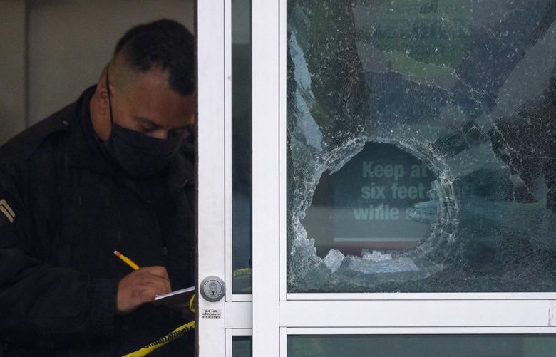 A police officer works behind a broken glass door at the scene where two people were struck by gunfire in a shooting at a Burlington store as part of a chain formerly known as Burlington Coat Factory in North Hollywood, Calif., Thursday, Dec. 23, 2021. (AP Photo/Ringo H.W. Chiu) NYOTK NYOTK