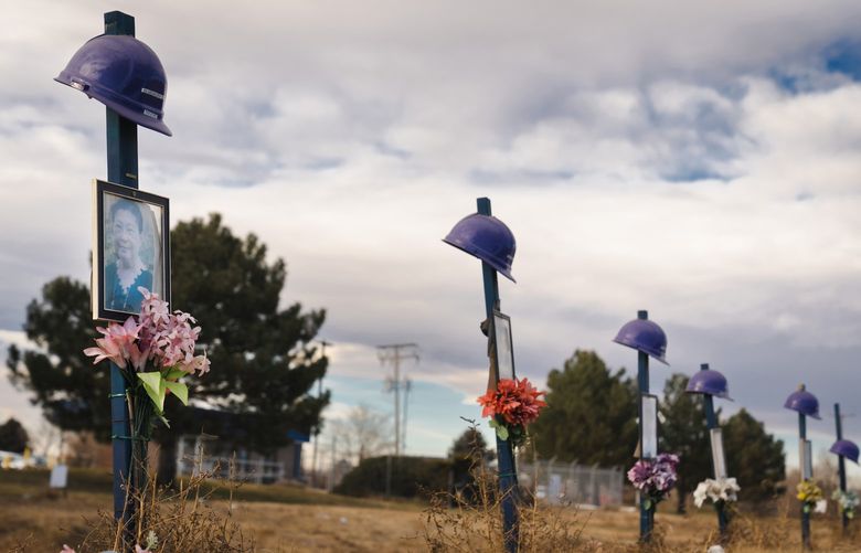 A memorial across from the JBS plant, a meat processing company, in Greeley, Colo., Dec. 19, 2021, includes a photo of Tin Aye, left, one of six employees who died in the pandemic. Workers say factories are still glossing over coronavirus safety, as the meatpackers that dominate beef production harvest record profits. (Erin Schaff/The New York Times)