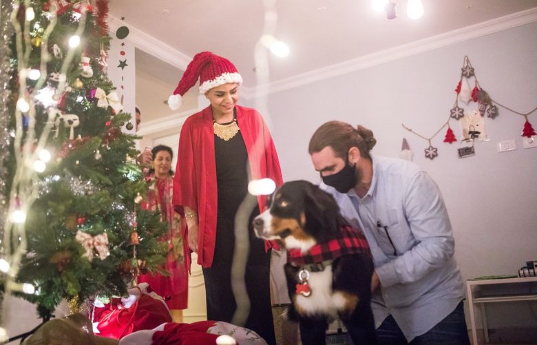 Umniah Alzahery and her husband, Mike Bounacklie, put a Christmas sweater on their dog as they prepared to celebrate Christmas at their home in Jeddah, Saudi Arabia on Dec. 23, 2021. Once officially banned, Christmas is coming out of hiding in the kingdom, as its ultra-constrictive religious rules are eased. (Iman Al-Dabbagh/The New York Times) XNYT50 XNYT50