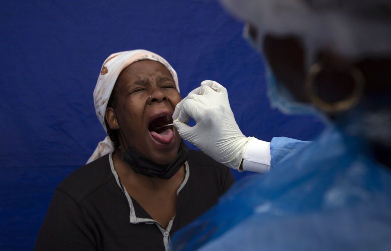 FILE â€” A throat swab is taken from a patient to test for COVID-19 at a facility in Soweto, South Africa, Dec. 2, 2021. South Africa’s noticeable drop in new COVID-19 cases in recent days may signal that the country’s dramatic omicron-driven wave has passed its peak, medical experts say. (AP Photo/Denis Farrell, File) XNE104 XNE104