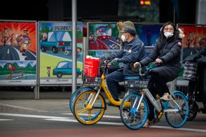 Bicyclists wearing face masks to protect against COVID-19 wait at an intersection in the central business district in Beijing, Thursday, Dec. 23, 2021. China has ordered the lockdown of as many as 13 million people in neighborhoods and workplaces in the northern city of Xi’an following a spike in coronavirus cases, setting off panic buying just weeks before the country hosts the Winter Olympics. (AP Photo/Mark Schiefelbein)