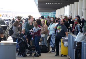 Travelers queue up at the Southwest Airlines curbside check-in area at Denver International Airport Sunday, Dec. 26, 2021, in Denver. Airlines canceled hundreds of flights Sunday, citing staffing problems tied to COVID-19 to extend the nation’s travel problems beyond Christmas. (AP Photo/David Zalubowski)
