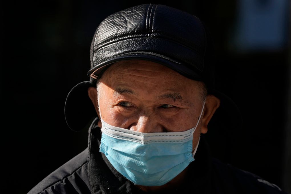 2021 年 12 月 14 日，星期二，一名戴着口罩的男子在中国北京的街道上抬起头。中国官方媒体称，2021 年 12 月 13 日星期一，已发现第一例 COVID-19 omicron 变体病例在中国大陆的天津市就在北京以东。 （美联社照片/吴汉冠）