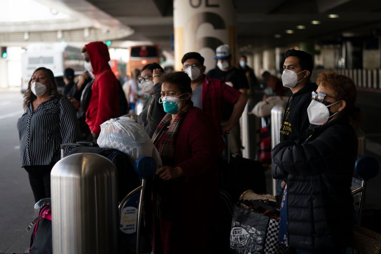 2021 年 12 月 20 日星期一，旅行者等待穿梭巴士抵达洛杉矶的洛杉矶国际机场。洛杉矶县公共卫生部周日报告了 3,500 多例新的 COVID-19 病例，其中一周内，每日新增病例增加了两倍。 （美联社照片/Jae C. Hong）
