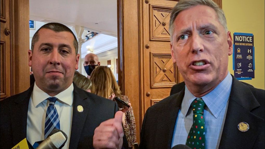 New Jersey Assembly member Brian Bergen, left, stands with fellow GOP Assembly member Erik Peterson, right, who speaks and gestures toward New Jersey State troopers blocking GOP lawmakers from entering the Assembly chamber because they did not show proof of a COVID-19 vaccination or a negative test, Thursday Dec. 2, 2021, in Trenton, N.J. The lawmakers decried the mandate, saying it was unconstitutional, though the troopers ultimately let the some of the legislators who declined to show their documents enter the chamber. It’s unclear why. A message seeking an explanation was left with the state police. (AP Photo/Mike Catalini)