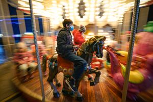 Children, some wearing face masks, enjoy a carousel ride at a Christmas fair in Bucharest, Romania, Saturday, Nov. 27, 2021. The Romanian capital will have three Christmas fairs open for public in the coming weeks and access to the venues will be conditioned by a COVID-19 green pas, proving the holder’s vaccination or recovery after the infection. (AP Photo/Vadim Ghirda)