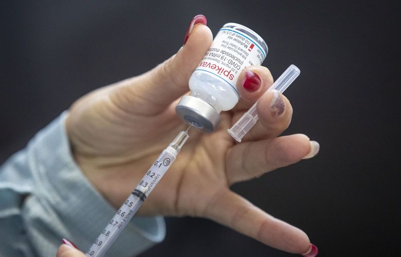 A person draws out Moderna vaccine during a drive through COVID-19 vaccine clinic at St. Lawrence College in Kingston, Ontario, on Sunday Jan.  2, 2022.  (Lars Hagberg /The Canadian Press via AP) LTH114 LTH114