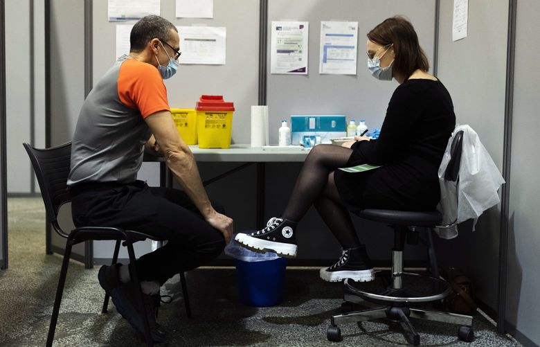 A man prepares to be vaccinated with Moderna’s COVID-19 vaccine, in a vaccination center, in Nantes, western France, Thursday, Dec. 30, 2021. France has vaccinated 77% of its population and is rushing out booster shots. But more than 4 million adults remain unvaccinated. (AP Photo/Jeremias Gonzales) PAR104 PAR104