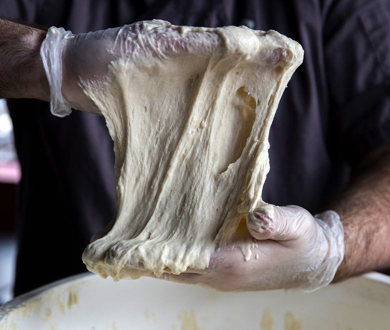 Will Grant, owner of That’s A Some Pizza, grabs some of his over 100-year-old sourdough starter from the Alaska gold rush to show at his pizza shop. (Amanda Snyder / The Seattle Times)