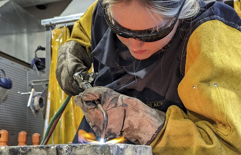 Clear Lake High School senior Emma Pingel uses an acetylene torch to weld steel plates together in her industrial-tech class, Dec. 1, 2021, in Clear Lake, Iowa. Pingel is taking her first industrial class this semester and is gaining skills in welding. She added that she jumped in without any prior knowledge, wanting basic understanding of how to weld for future use. (Lisa Grouette/Globe-Gazette via AP) IAMAS102 IAMAS102