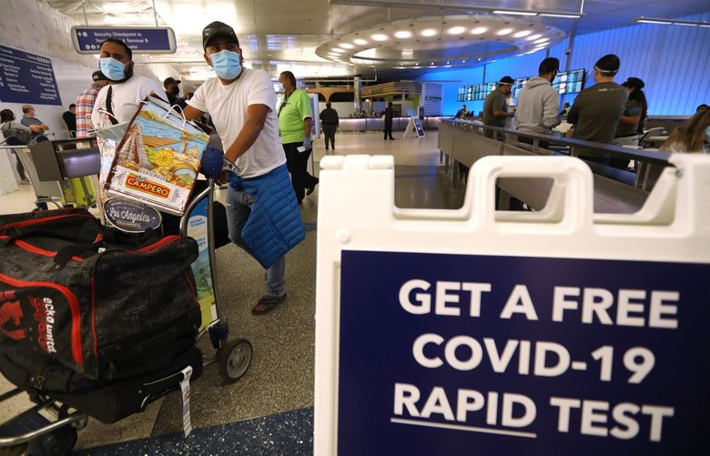 Arriving travelers walk past a sign directing them to free COVID-19 rapid tests at the Tom Bradley International Terminal at Los Angeles International Airport, Friday, Dec. 3, 2021. (Genaro Molina/Los Angeles Times/TNS) 36732326W 36732326W