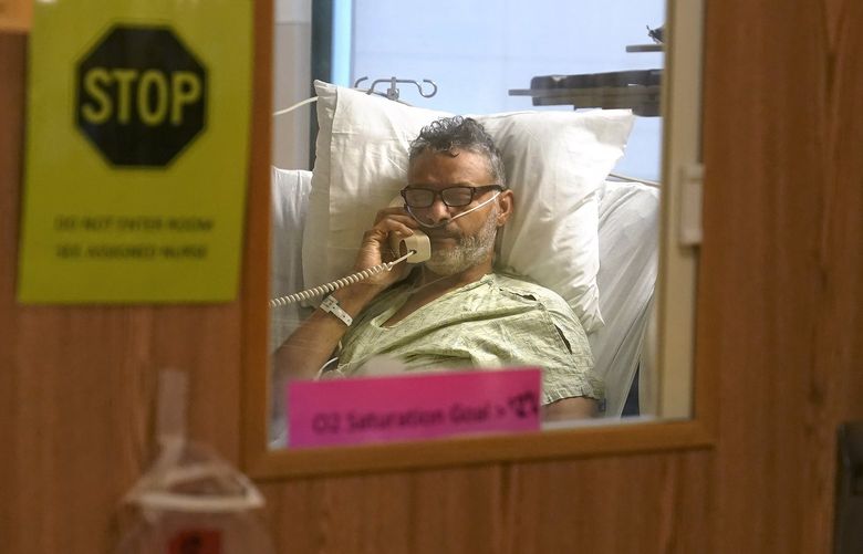 Patient Fred Rutherford, of Claremont, N.H., who is recovering from COVID-19, speaks on a telephone with a reporter from The Associated Press from an isolation room at Dartmouth-Hitchcock Medical Center, in Lebanon, N.H., Monday, Jan. 3, 2022. Hospitals like this medical center, the largest in New Hampshire, are overflowing with severely ill, unvaccinated COVID-19 patients from northern New England. If he returns home, Rutherford said, he promises to get vaccinated and tell others to do so, too. (AP Photo/Steven Senne) NYAG303 NYAG303