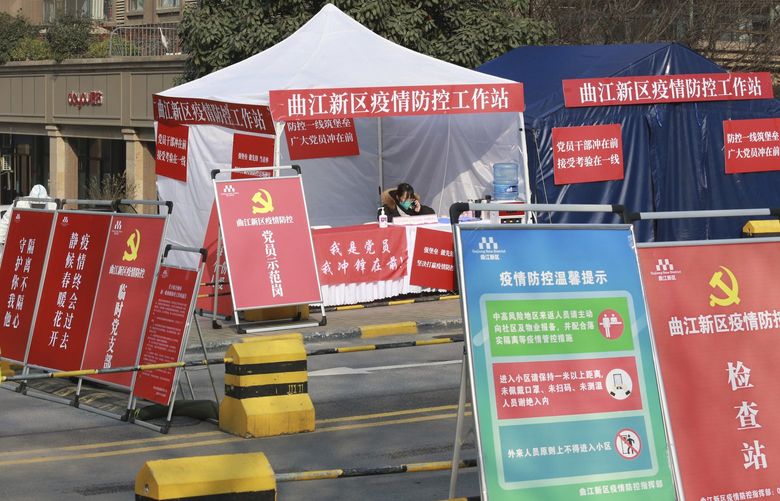 A government worker mans a pandemic checkpoint outside a residential block in Xi’an city in northwest China’s Shaanxi province Monday, Jan. 3, 2022. Authorities in the northern Chinese city of Xi’an say they can provide food, health care and other necessities for the roughly 13 million under an almost two-week old lockdown. But some residents describe difficulties obtaining supplies and frustration and the economic impact on the city that is home to the famed Terracotta warriors, along with major industries. (Chinatopix Via AP) XHG802 XHG802