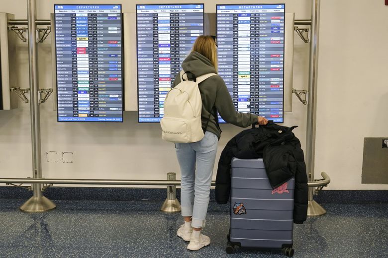 周四，美国有 2,000 多个航班被取消，因为航空公司继续努力恢复因冠状病毒感染导致的恶劣天气和人员短缺而陷入困境的航班网络。 上图，本周早些时候，一名乘客在迈阿密国际机场检查出发板。 （Marta Lavandier / 美联社）