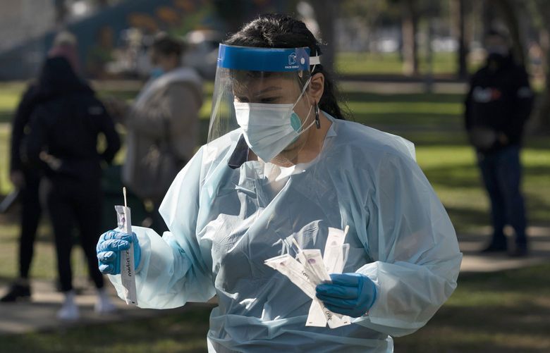 Medical assistant Leslie Powers carries swab samples collected from people to process them on-site at a COVID-19 testing site in Long Beach, Calif., Thursday, Jan. 6, 2022. (AP Photo/Jae C. Hong) CAJH116 CAJH116