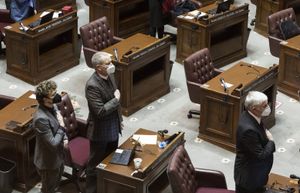 Senators stand during start of the legislative session at the state Capitol in Olympia on Monday, Jan. 10, 2022. About a dozen senators showed up in-person Monday for the start of the session, while the rest attended remotely.