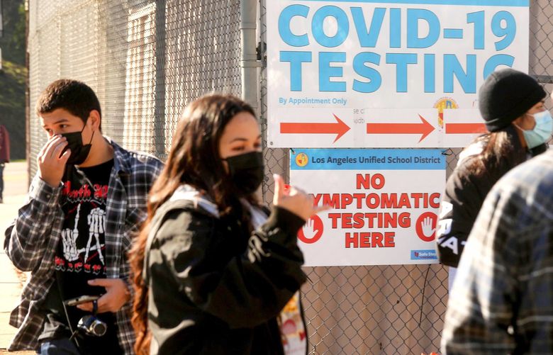 A support worker, second from left, directs Los Angeles Unified School District students and staff who wait in line for a COVID-19 test at a walk-up site at the El Sereno Middle School in the El Sereno neighborhood of Los Angeles on Jan. 4, 2022. (Genaro Molina/Los Angeles Times/TNS) 37242389W