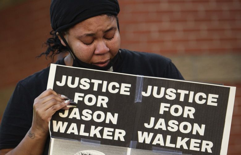 Pandora Harrington, right, cries as she holds a sign with an image of Jason Walker during a demonstration in front of the Fayetteville Police Department, Sunday, Jan. 9, 2022, in Fayetteville, N.C. Walker, 37, was shot and killed on Saturday by an off-duty deputy with the Cumberland County Sheriff’s Office. (Andrew Craft/The Fayetteville Observer via AP) NCFAY103 NCFAY103