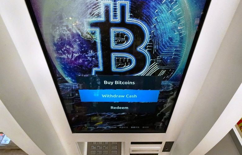 FILE – In this Feb. 9, 2021 file photo, the Bitcoin logo appears on the display screen of a crypto currency ATM at the Smoker’s Choice store in Salem, N.H.    According to experts, before dabbling in crypto, it helps to get your financial house in order and that means setting money goals, building your savings and contributing to retirement accounts and then educate yourself on how crypto works.  (AP Photo/Charles Krupa, File) NYBZ203