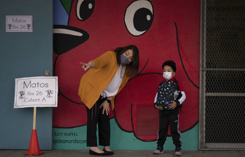FILE – Kindergarten teacher Lilia Matos and her student Jesus Mendez stand outside their classroom on the first day of in-person learning at Heliotrope Avenue Elementary School in Maywood, Calif., Tuesday, April 13, 2021. California is making it easier for school districts to hire teachers and other employees amid staffing shortages brought on by the latest surge in coronavirus cases, the governor said Tuesday, Jan. 11, 2022. (AP Photo/Jae C. Hong, File) LA254 LA254
