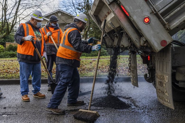 A Seattle Department of Transportation crew works on filling potholes along Beacon Avenue South in Seattle. (Daniel Kim / The Seattle Times)