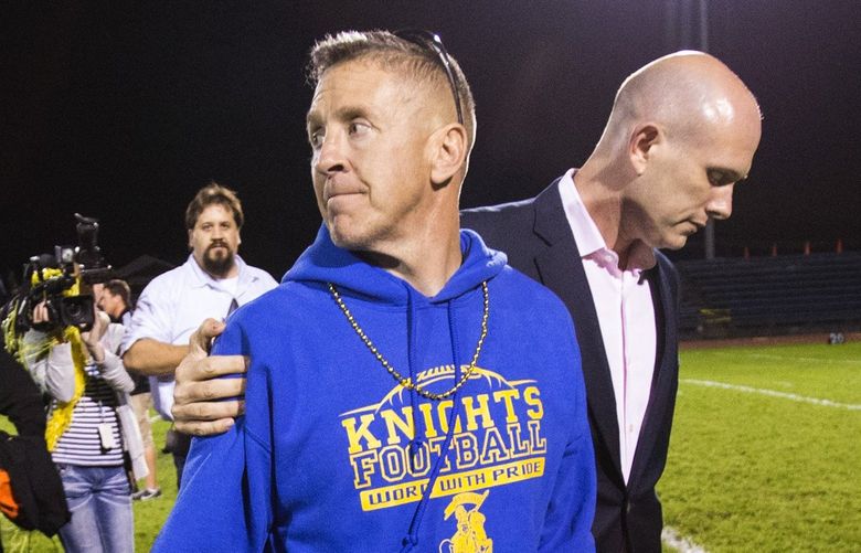 Bremerton coach Joe Kennedy walks off the field with his lawyer after kneeling to pray at the 50 yard line after the game at Bremerton Memorial Stadium on Friday, Oct. 16, 2015. Kennedy plans to continue his 7-year tradition of kneeling to pray at the 50-yard line after the game, disobeying district orders. On Sept. 17, District Superintendent Aaron Leavell wrote to Kennedy, saying that his actions were in violation of district policies and that the activities would have to end.