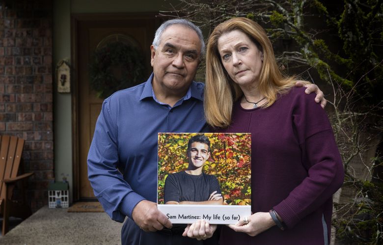 Jolayne Houtz and her husband Hector Martinez hold a book Jolayne made for her son Sam Martinez for a  high school graduation gift. Sam died of alcohol poisoning while pledging a fraternity at Washington State University in 2019. Jolayne and Hector are now supporting two bills in Olympia that would provide education surrounding hazing and strengthen the penalty for it. (Ellen M. Banner / The Seattle TImes)