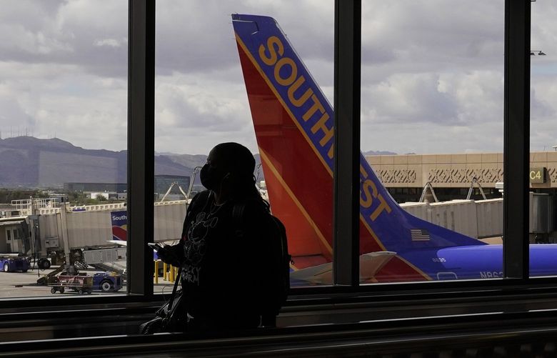 FILE – A passenger walks past a Southwest Airlines plane at Sky Harbor International Airport in Phoenix, March 26, 2021. AT&T and Verizon have agreed to delay the launch of a new slice of 5G service by two weeks after airlines and the nation’s aviation regulator complained about potential interference with systems on board planes. (AP Photo/Sue Ogrocki, File) AZSO301 AZSO301