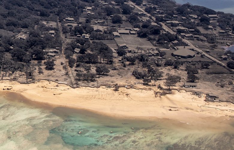 In this photo provided by the New Zealand Defense Force, volcanic ash covers roof tops and vegetation in an area of Tonga, Monday, Jan. 17, 2022. Thick ash on an airport runway was delaying aid deliveries to the Pacific island nation of Tonga, where significant damage was being reported days after a huge undersea volcanic eruption and tsunami. (CPL Vanessa Parker/NZDF via AP) SYD108 SYD108