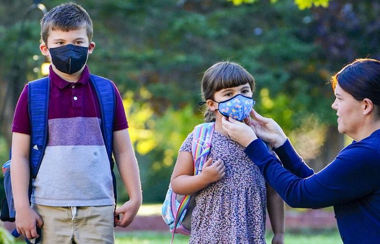 FILE – In this Oct. 7, 2021, file photo, Sarah Staffiere adjusts a face covering on her daughter, Natalie, before school in Waterville, Maine. Tumbling COVID-19 case counts have some schools around the U.S. considering relaxing their mask rules, but deaths nationally have been ticking up over the past few weeks, some rural hospitals are showing signs of strain, and cold weather is setting in. (AP Photo/Robert F. Bukaty, File) NYAG102